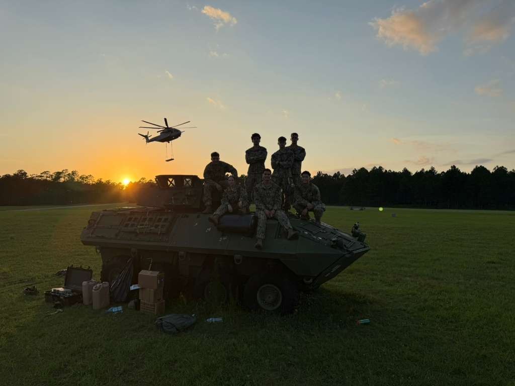 Midshipmen with a light armored vehicle as a CH-53 operates overhead during MAGTF