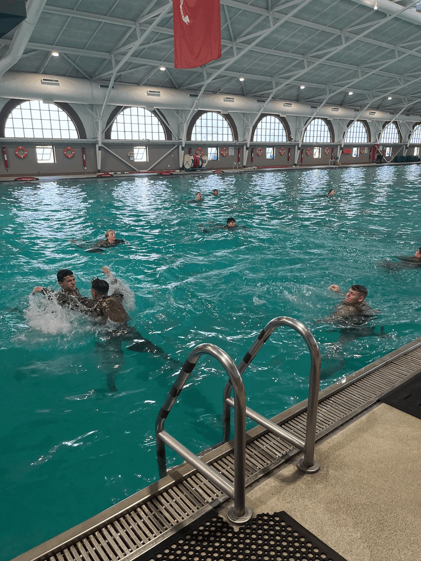 Midshipmen practice water survival techniques in full uniform at the pool